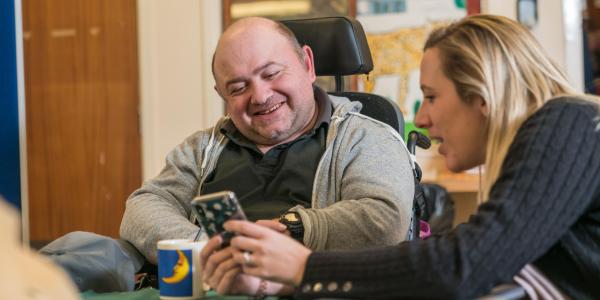 Male wheelchair user and female staff member looking at a phone