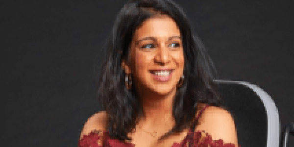 Arunima Misra wearing a red dress sat in her wheelchair and smiling to the side