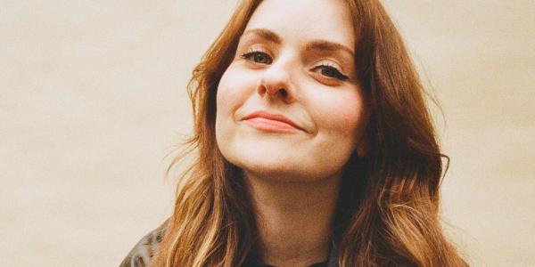 Head shot of Isobel a Caucasian woman with long brown hair smiling at the camera