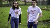 A woman and man looking at the camera laughing wearing white tshirts with orange writing saying "Disabled looks like me"