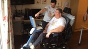 Gloucestershire House resident Dave Evans on an adapted bike with volunteer Florian pointing on the screen