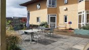 Back garden with a paved patio and charcoal coloured table and chairs 