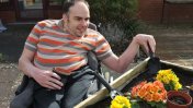 A dark haired resident in a wheelchair potting some flowerpots in a garden
