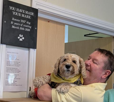 Paul and Bonnie next to the plaque, which reads: “You have made your mark. Bonnie ‘PAT’ dog. 10 years of visiting. 30 March 2026
