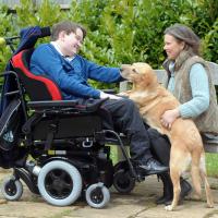 Tom in his wheelchair with his mum and a guide dog