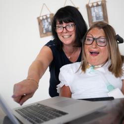 A female wheelchair user and her carer looking at a laptop screen